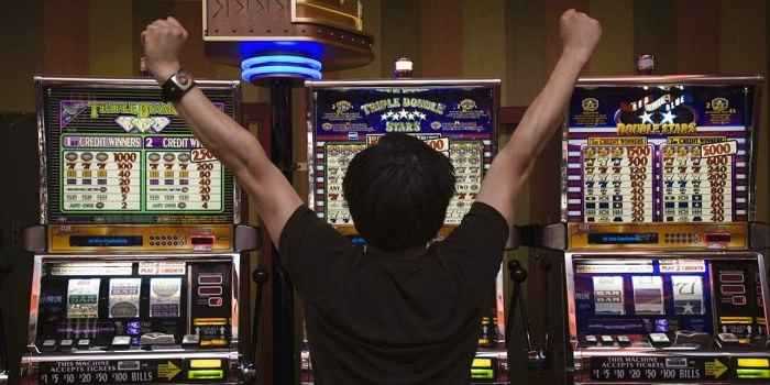 man cheering in front of slot machines