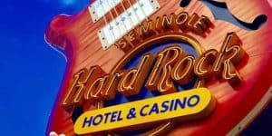 Close-up of a Hard Rock Hotel & Casino neon sign featuring a guitar shape against a bright blue sky